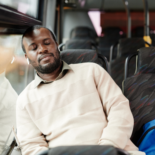 Man sleeping on bus with headphones on.