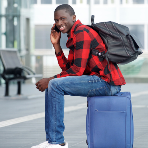 Man in red plaid shirt sits on luggage.